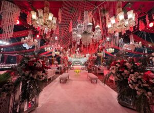 indoor baraat setup, royal red theme, carpeted walkway, floral decor